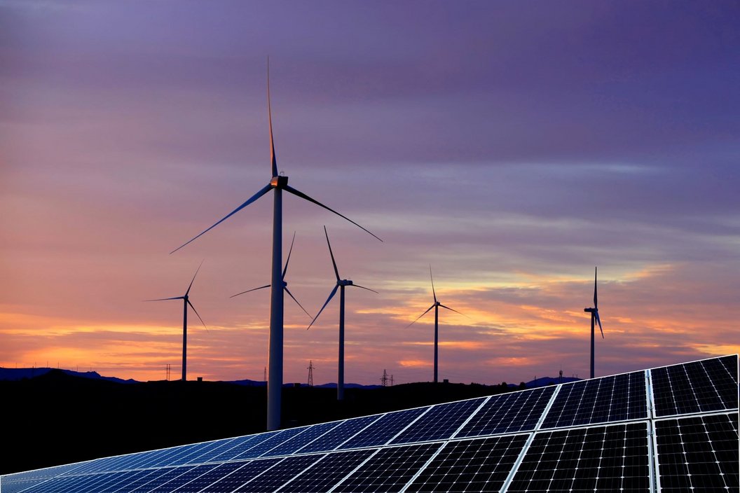 Solar panels and wind turbines at sunset